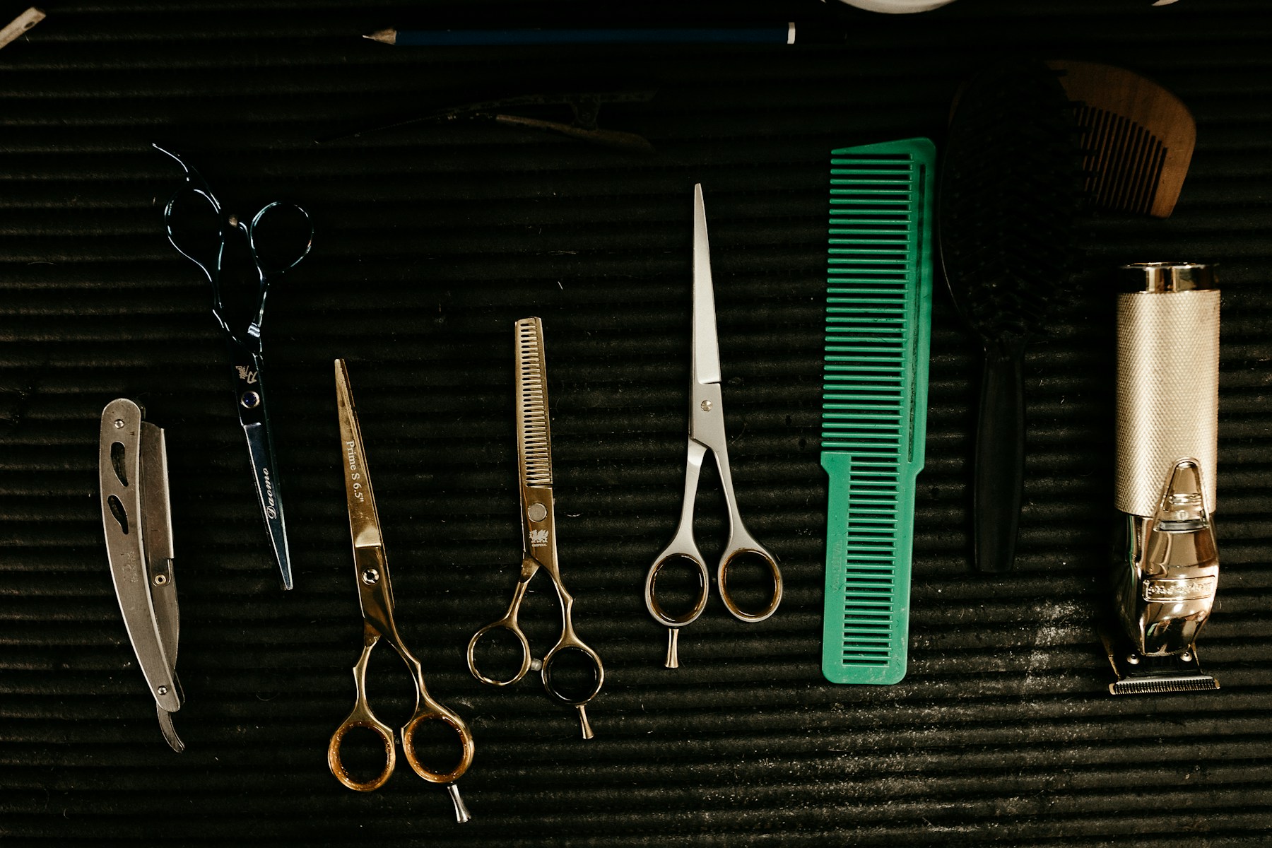 Scissors, a comb and clippers laid out on a barber’s work mat